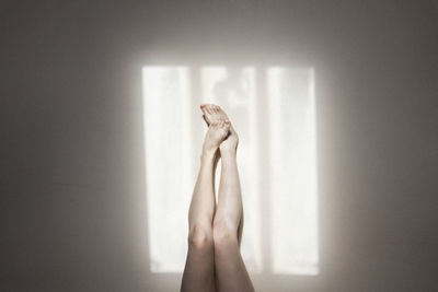 Midsection of woman standing against wall at home