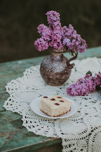 Close-up of fresh purple flowers on table and a slice of cheese pie