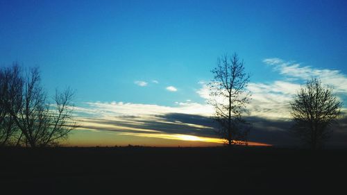 Silhouette of trees on landscape against sky at sunset