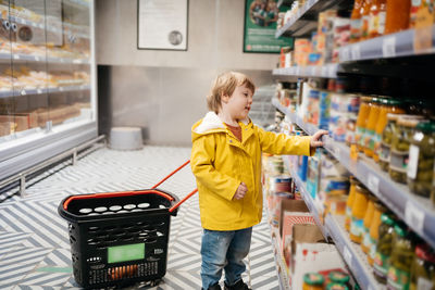 Child in the market with a grocery cart, chooses a product