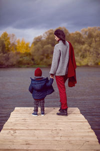 Woman in a sweater with a child standing on a bridge cold autumn on the river