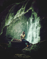 Full length of woman sitting on rock