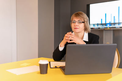 Mid adult woman using mobile phone while sitting on table