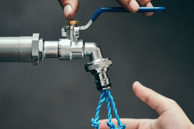 Close-up of man holding tap and blue string