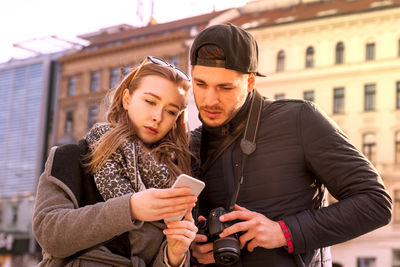 Happy young man using smart phone in city