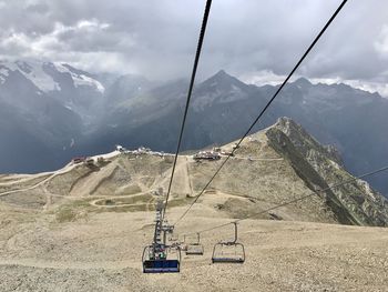 Overhead cable car over mountains against sky