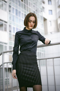 Young woman looking down while standing by railing