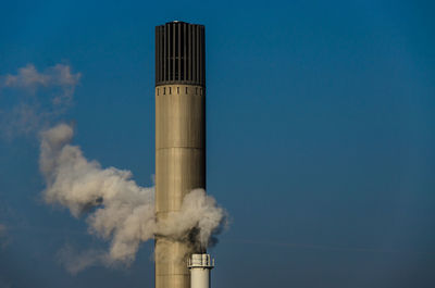 Smoke emitting from chimney against blue sky