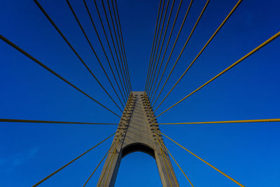 Low angle view of suspension bridge against blue sky