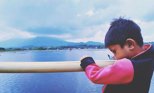 Boy looking at sea against sky