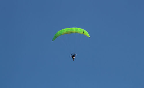 Low angle view of person paragliding against clear blue sky