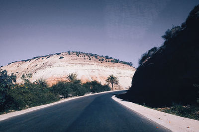 Road by trees against clear sky