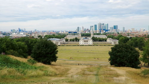 Trees on field against sky in city