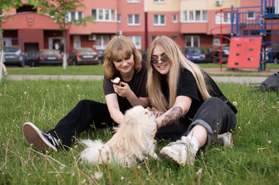 Pomeranian, white dog, two girls, eating ice cream, sitting on the grass