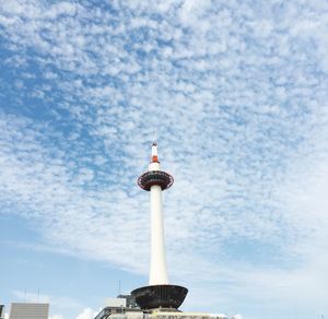 Low angle view of communications tower against cloudy sky