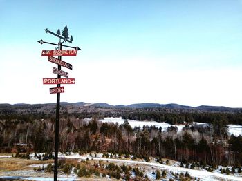 Road sign on snow covered mountain against sky