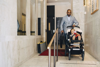 Full length of man pushing girl in carriage outside house