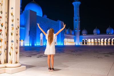 Rear view of woman standing against blue sky at night