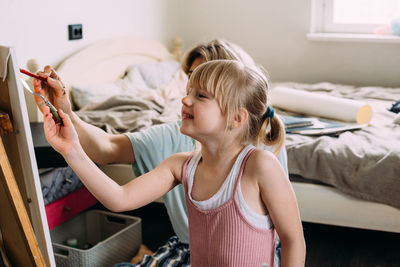 Full length of girl holding bed at home