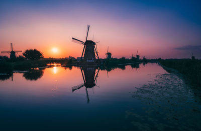 Silhouette of traditional windmill against sky during sunset