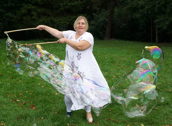 Portrait of smiling young woman with bubbles in park