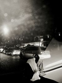 Man on car against sky in city at night