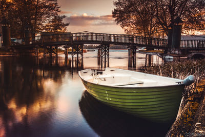 Boats moored on river by trees against sky