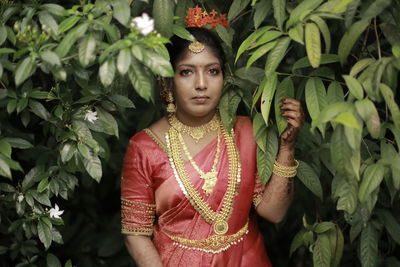 Portrait of young woman standing against plants