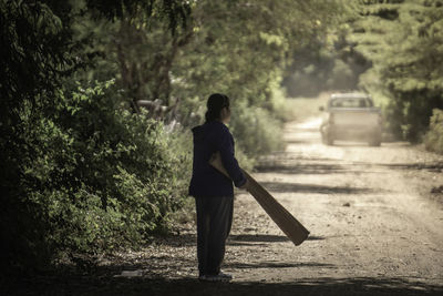 Rear view of woman walking on road amidst trees