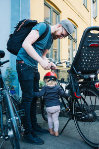 Full length of father and daughter standing by bicycle on street