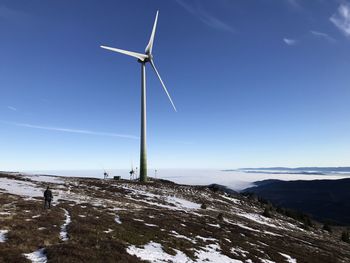 Wind turbines on snowcapped landscape against sky