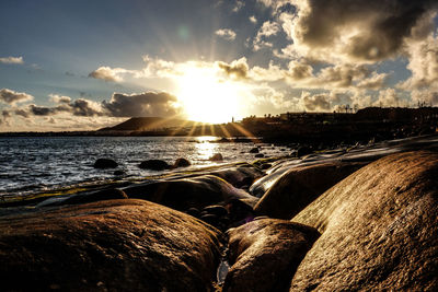 Rocks in sea against sky during sunset