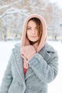 Portrait of smiling young woman standing against trees during winter