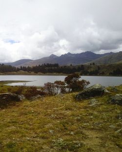 Scenic view of lake and mountains against cloudy sky