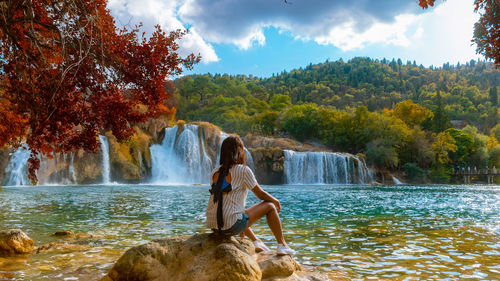 Rear view of woman standing by waterfall