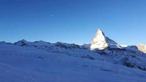 Scenic view of snowcapped mountains against clear blue sky