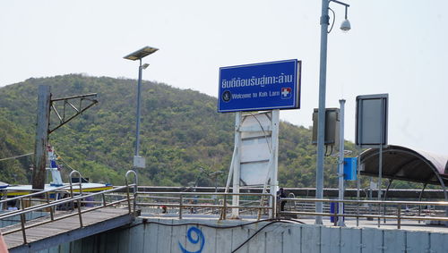 Information sign on street light against sky