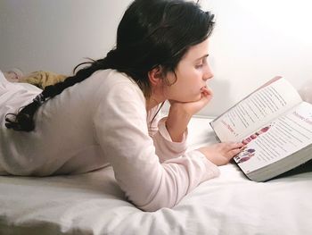 Young woman using mobile phone on bed at home