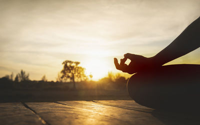 Silhouette person with hands against sky during sunset