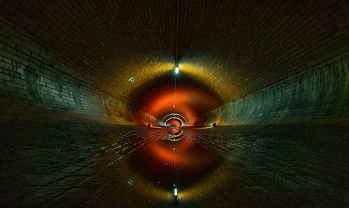 Reflection of illuminated tunnel on puddle