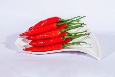 Close-up of red chili pepper on table against white background