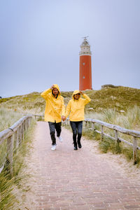 Full length of couple walking on footpath against clear sky