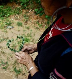 Rear view of man holding flower in field