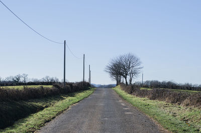 Road amidst field against clear sky