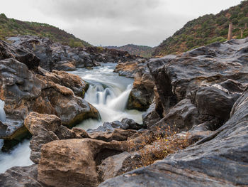 Scenic view of waterfall against sky