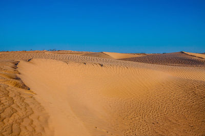 Sand dunes in desert against clear blue sky