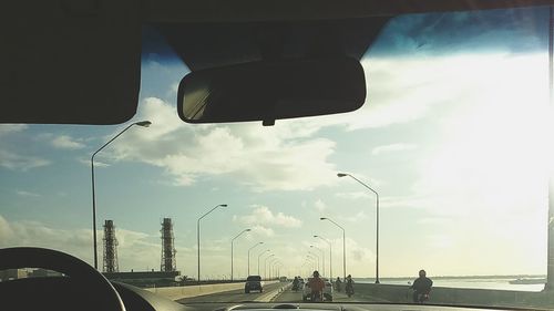 Cars on road against cloudy sky