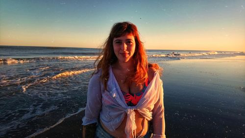 Portrait of woman standing at beach against sky