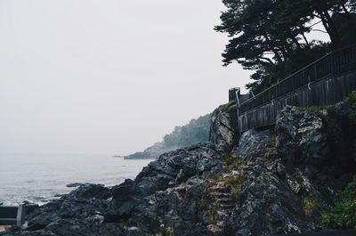 View of rocky cliff by sea against clear sky