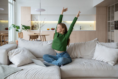 Young woman sitting on bed at home